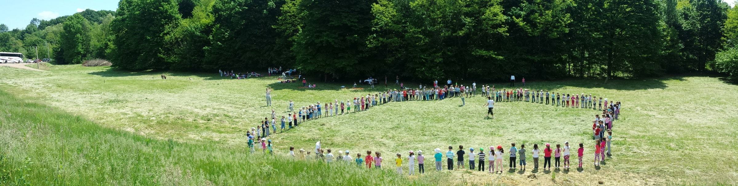 Deca u velikom krugu na livadi uz šumu