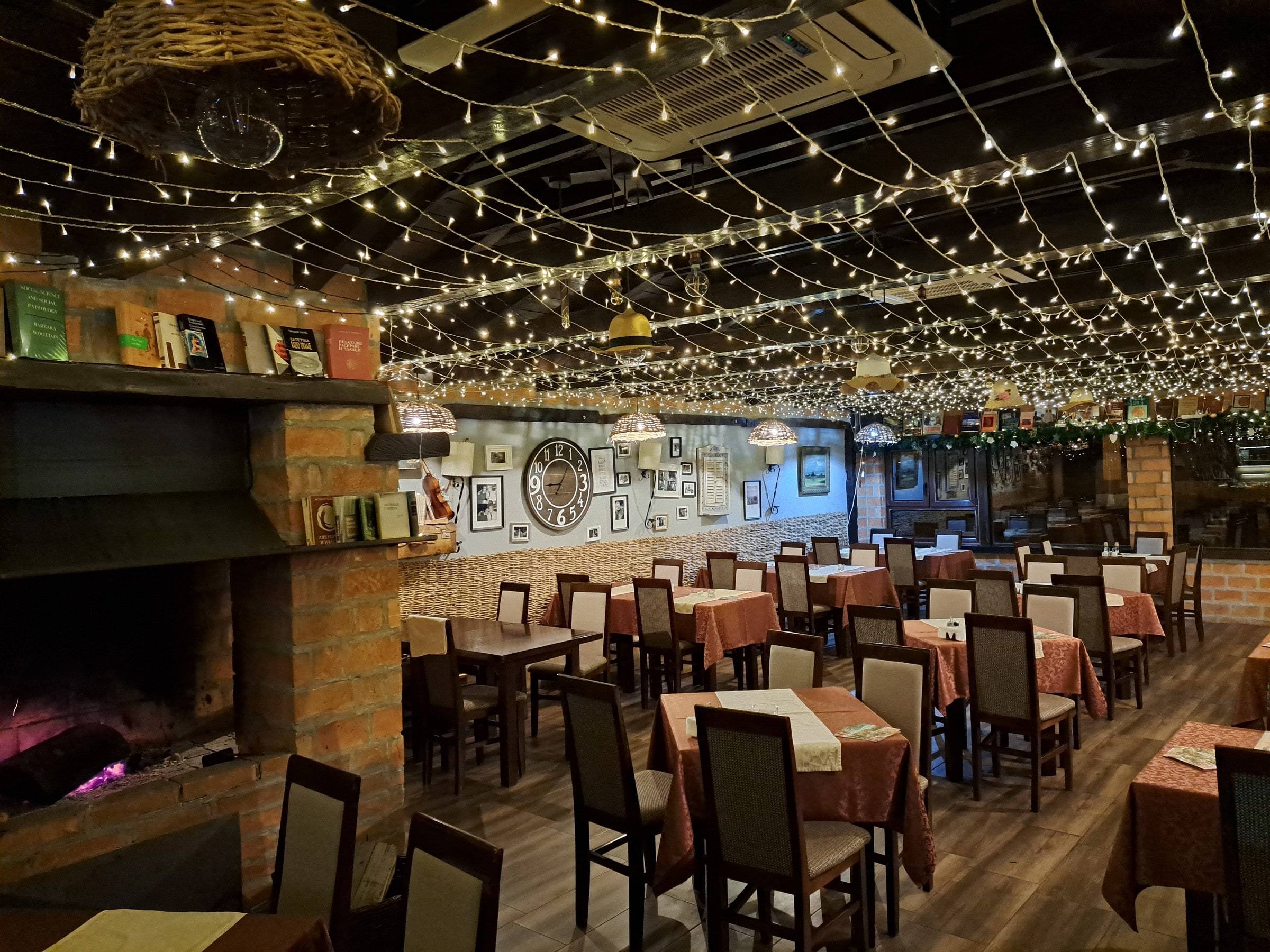 Restoran Dobrica uveče: kamin od cigle, stolovi i plafon pod lampicama