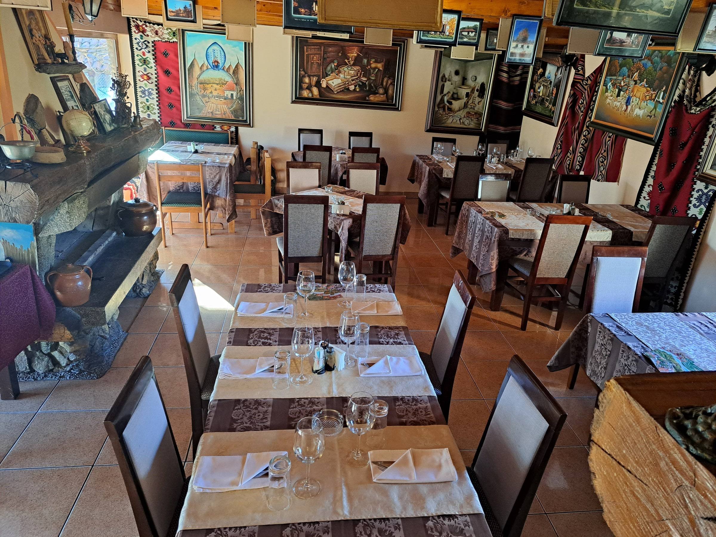Restoran Dobrosav: postavljeni stolovi i zidovi puni šarenih naivnih slika