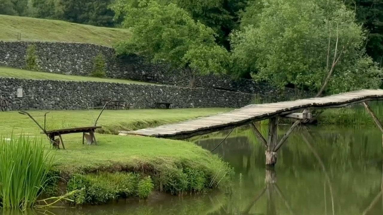 Drveni most preko jezera, u vodi odraz mosta i krošnji