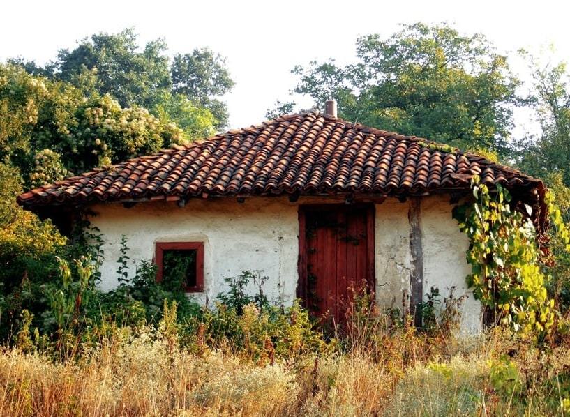 Bela kuća sa crvenim krovom obrasla zelenilom