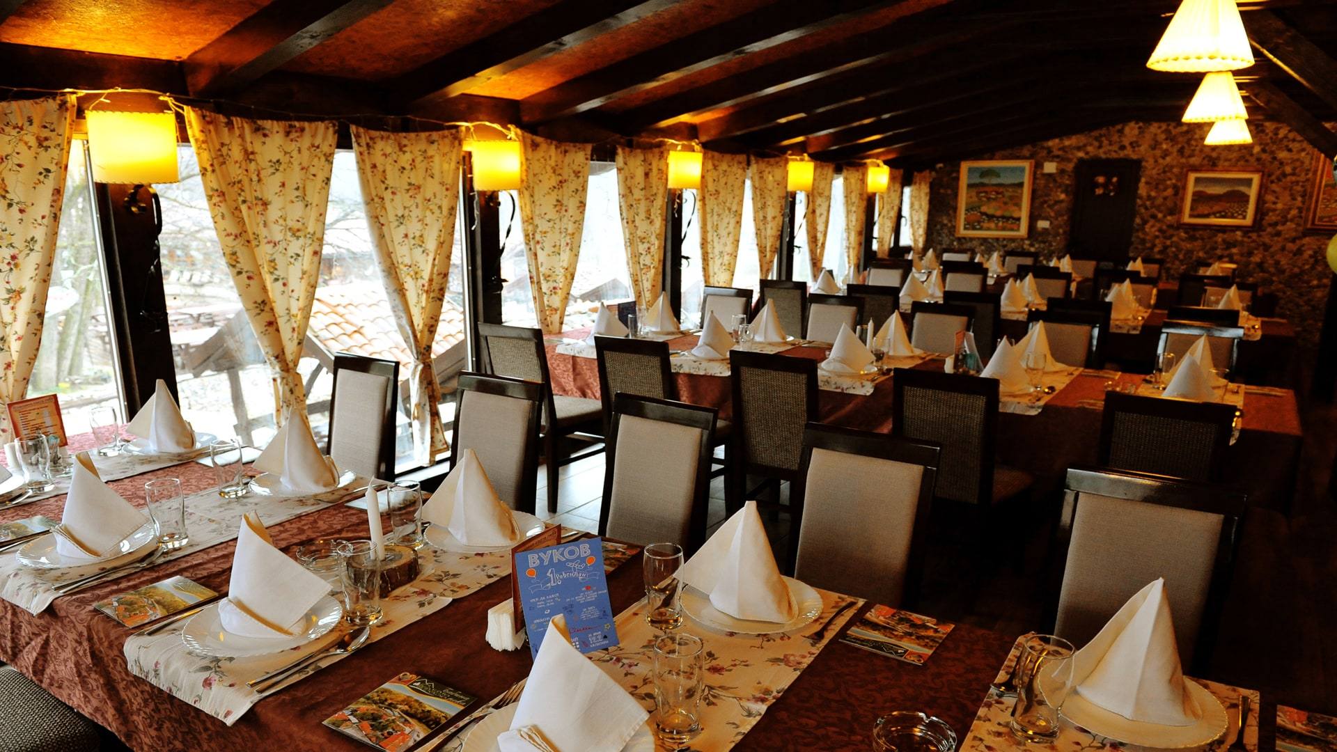 Restoran Dobrosav sa drvenim gredama, lampama i pogledom na baštu